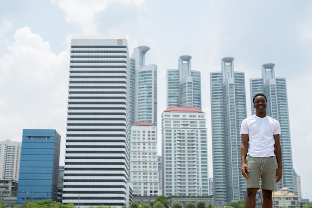 Jeune bel homme africain se détendre dans le parc de Bangkok, Thai