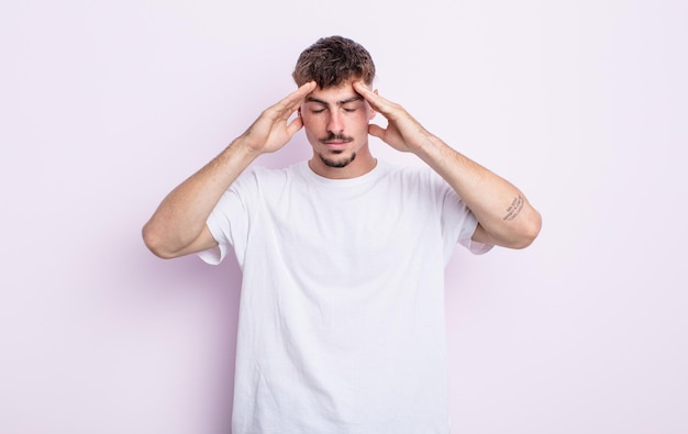 Jeune bel homme à l'air concentré, réfléchi et inspiré, remue-méninges et imaginant avec les mains sur le front