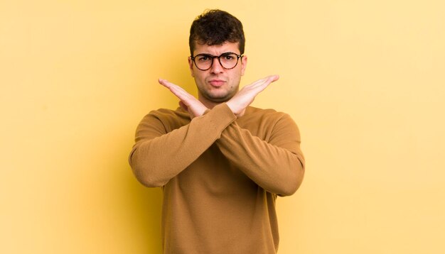 Jeune bel homme à l'air ennuyé et malade de votre attitude en disant assez de mains croisées devant vous disant d'arrêter