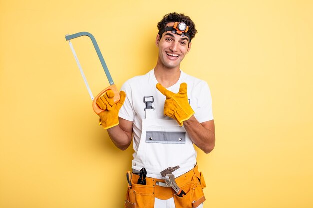 Jeune bel homme à l'air excité et surpris en pointant sur le côté. concept de réparation de bricoleur