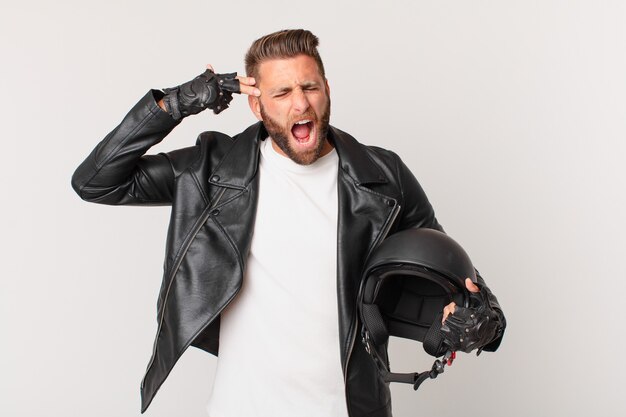 Jeune bel homme à l'air malheureux et stressé, geste de suicide faisant signe d'arme à feu. concept de casque de moto