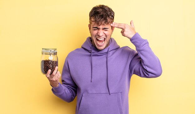 Jeune bel homme à l'air malheureux et stressé, geste de suicide faisant signe d'arme à feu. concept de grains de café