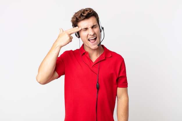 Jeune bel homme à l'air malheureux et stressé, geste de suicide faisant signe d'arme à feu. concept de télévendeur