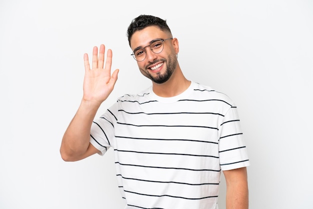 Jeune bel homme arabe isolé sur fond blanc saluant avec la main avec une expression heureuse