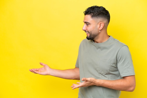 Jeune bel homme arabe isolé sur fond jaune avec une expression surprise tout en regardant de côté