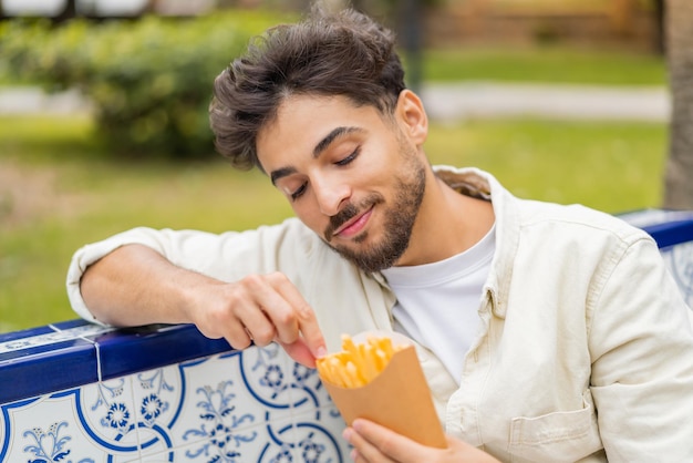 Jeune bel homme arabe tenant des chips frites à l'extérieur