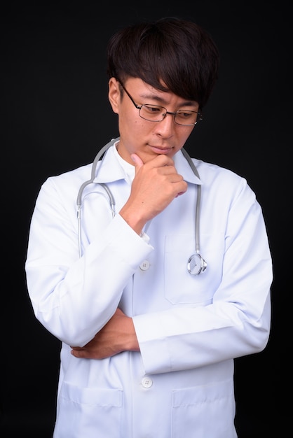 jeune bel homme asiatique médecin sur noir