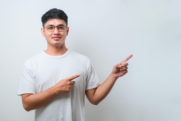 Jeune bel homme asiatique portant une chemise décontractée avec un grand sourire sur le visage pointant avec le doigt de la main sur le côté en regardant la caméra