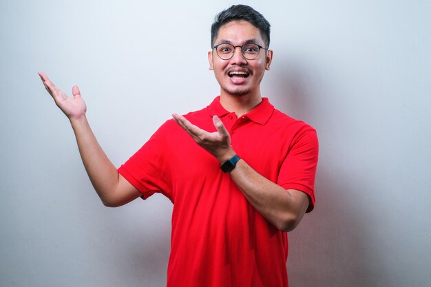 Jeune bel homme asiatique portant une chemise décontractée pointant quelque chose de son côté avec ses deux mains