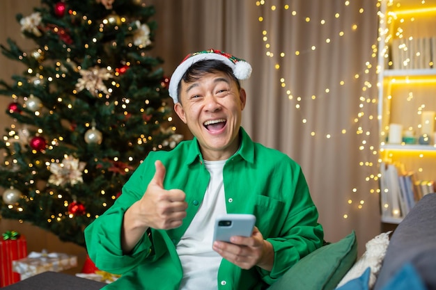 Un jeune bel homme asiatique tient un téléphone dans ses mains est heureux d'avoir reçu de bonnes nouvelles à la veille de