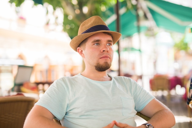 Jeune bel homme assis dans un café de la rue.