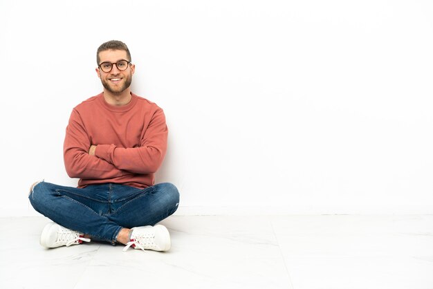 Jeune bel homme assis sur le sol avec les bras croisés et impatient