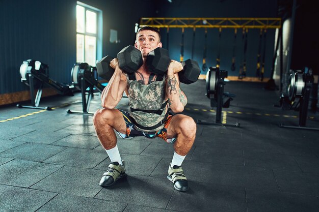 Jeune et bel homme athlète faisant des exercices pour les muscles des mains d'haltères dans la salle de gym. Crossfit et concept de santé