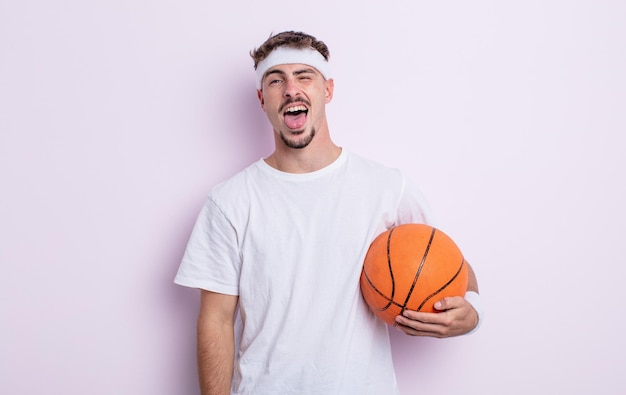 Jeune bel homme avec une attitude joyeuse et rebelle, plaisantant et tirant la langue. concept de basket-ball