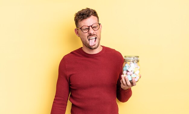 Jeune bel homme avec une attitude joyeuse et rebelle, plaisantant et tirant la langue. concept de bonbons à la gelée