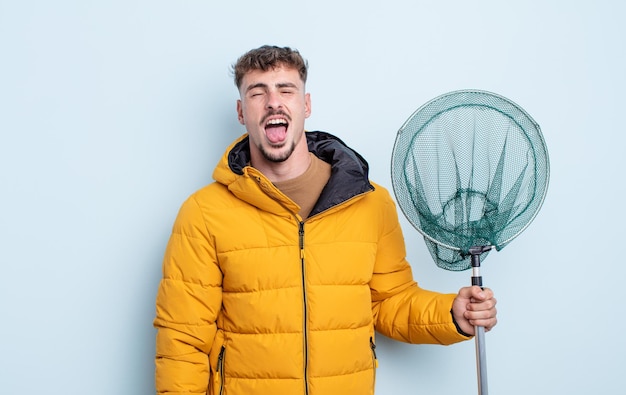 Jeune bel homme avec une attitude joyeuse et rebelle, plaisantant et tirant la langue. concept de pêcheur