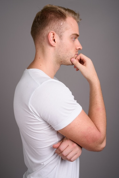 Jeune bel homme aux cheveux blonds contre gris