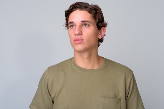 Jeune bel homme aux cheveux ondulés portant une chemise verte