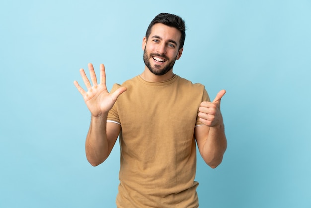 Jeune bel homme avec barbe isolé comptant six avec les doigts