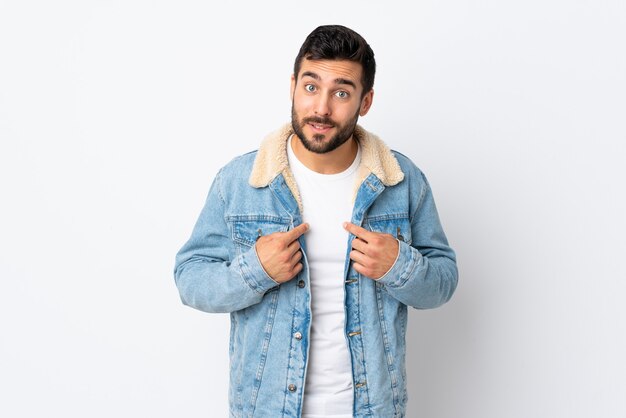 Jeune bel homme avec barbe isolé sur fond blanc pointant vers soi