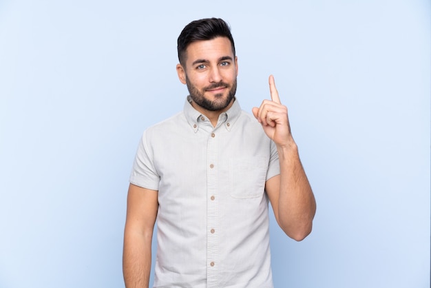 Jeune bel homme avec barbe isolé pointant avec l'index une excellente idée