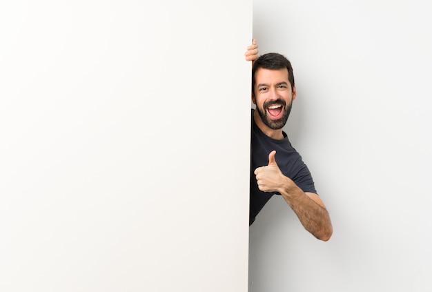 Jeune bel homme à la barbe tenant une grande pancarte vide