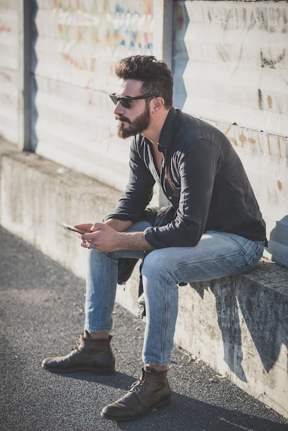 Jeune bel homme barbu attrayant beau modèle à l&#39;aide de smartphone