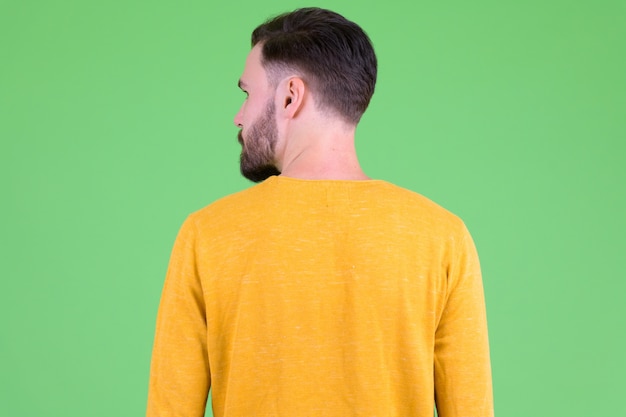 Jeune bel homme barbu contre chroma key avec mur vert