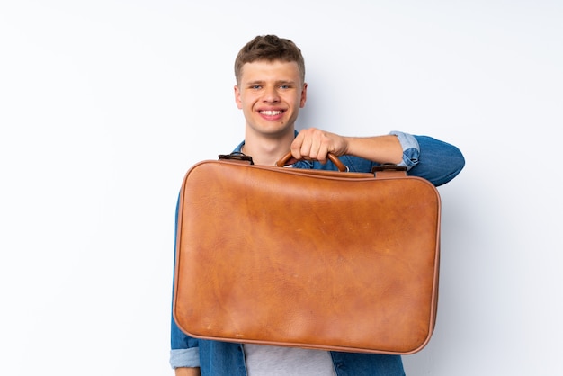 Jeune bel homme sur blanc isolé tenant une mallette vintage