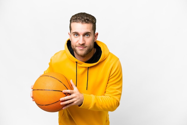 Jeune bel homme blond sur fond blanc isolé jouant au basket-ball