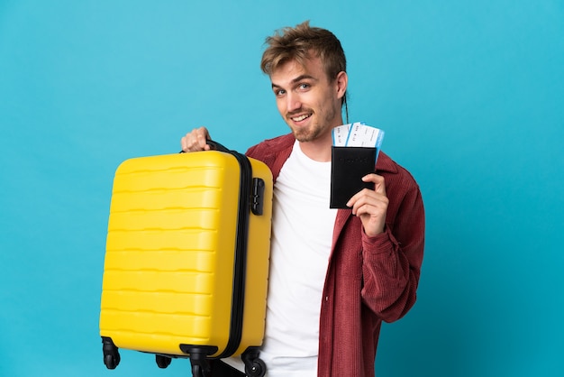 Jeune bel homme blond isolé en vacances avec valise et passeport