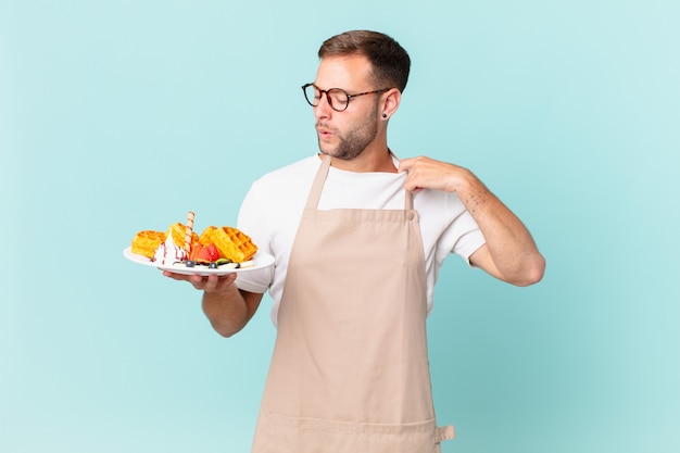 Jeune bel homme blond stressé, anxieux, fatigué et frustré. concept de cuisson des gaufres