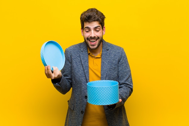 Jeune bel homme avec une boîte sur fond orange