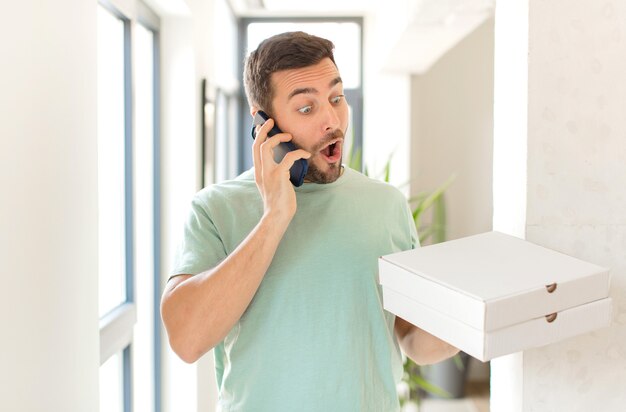 Jeune bel homme avec des boîtes de pizza à emporter à la maison