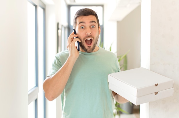 Jeune bel homme avec des boîtes de pizza à emporter à la maison