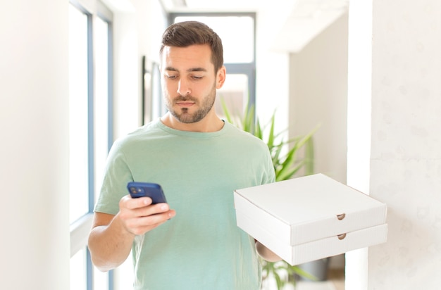 Jeune bel homme avec des boîtes de pizza à emporter à la maison