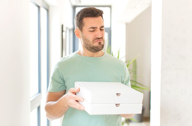 Jeune bel homme avec des boîtes de pizza à emporter à la maison