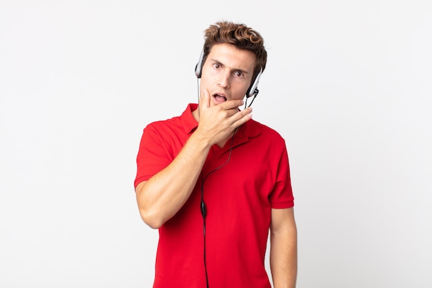 Jeune bel homme avec la bouche et les yeux grands ouverts et la main sur le menton. concept de télévendeur