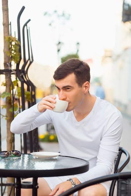 Jeune bel homme buvant du café