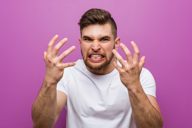 Jeune bel homme caucasien bouleversé crier avec les mains tendues.