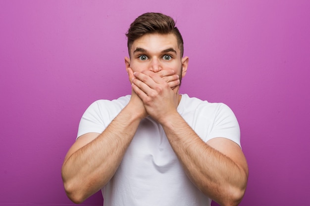 Jeune bel homme caucasien choqué bouche coning avec les mains.