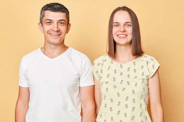 Jeune bel homme caucasien et femme souriante et regardant la caméra isolée sur fond beige famille portant des vêtements décontractés exprimant le bonheur