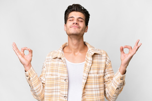 Jeune bel homme caucasien sur fond blanc isolé dans une pose zen