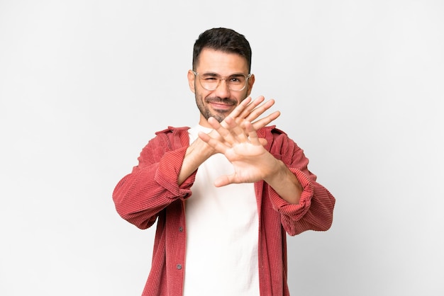 Jeune bel homme caucasien sur fond blanc isolé nerveux s'étendant les mains vers l'avant