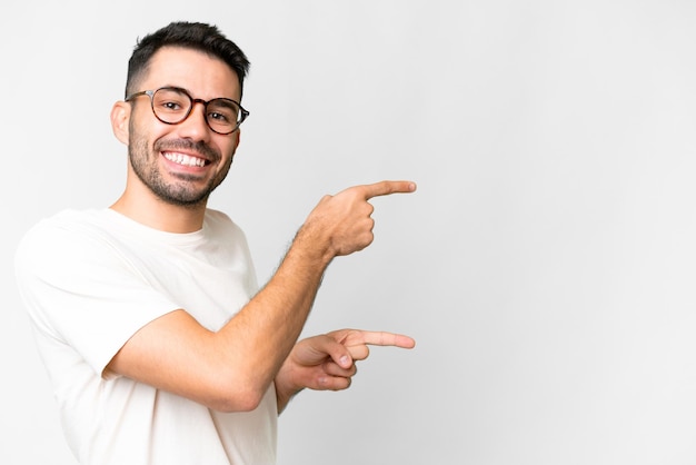 Jeune bel homme caucasien sur fond blanc isolé, pointant le doigt sur le côté et présentant un produit