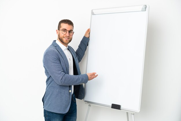 Jeune bel homme caucasien isolé sur blanc donnant une présentation sur tableau blanc