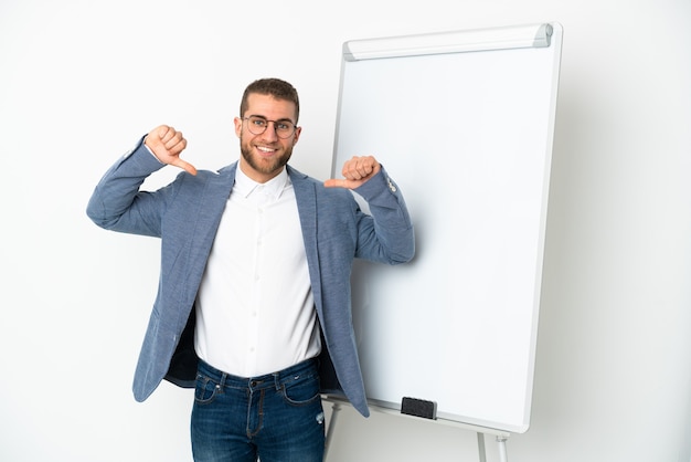 Jeune bel homme caucasien isolé donnant une présentation sur tableau blanc et fier