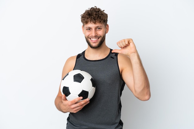 Jeune bel homme caucasien isolé sur fond blanc avec ballon de foot et fier de lui