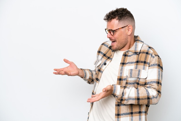 Jeune bel homme caucasien isolé sur fond blanc avec une expression de surprise tout en regardant de côté