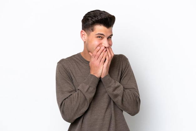 Jeune bel homme caucasien isolé sur fond blanc heureux et souriant couvrant la bouche avec les mains